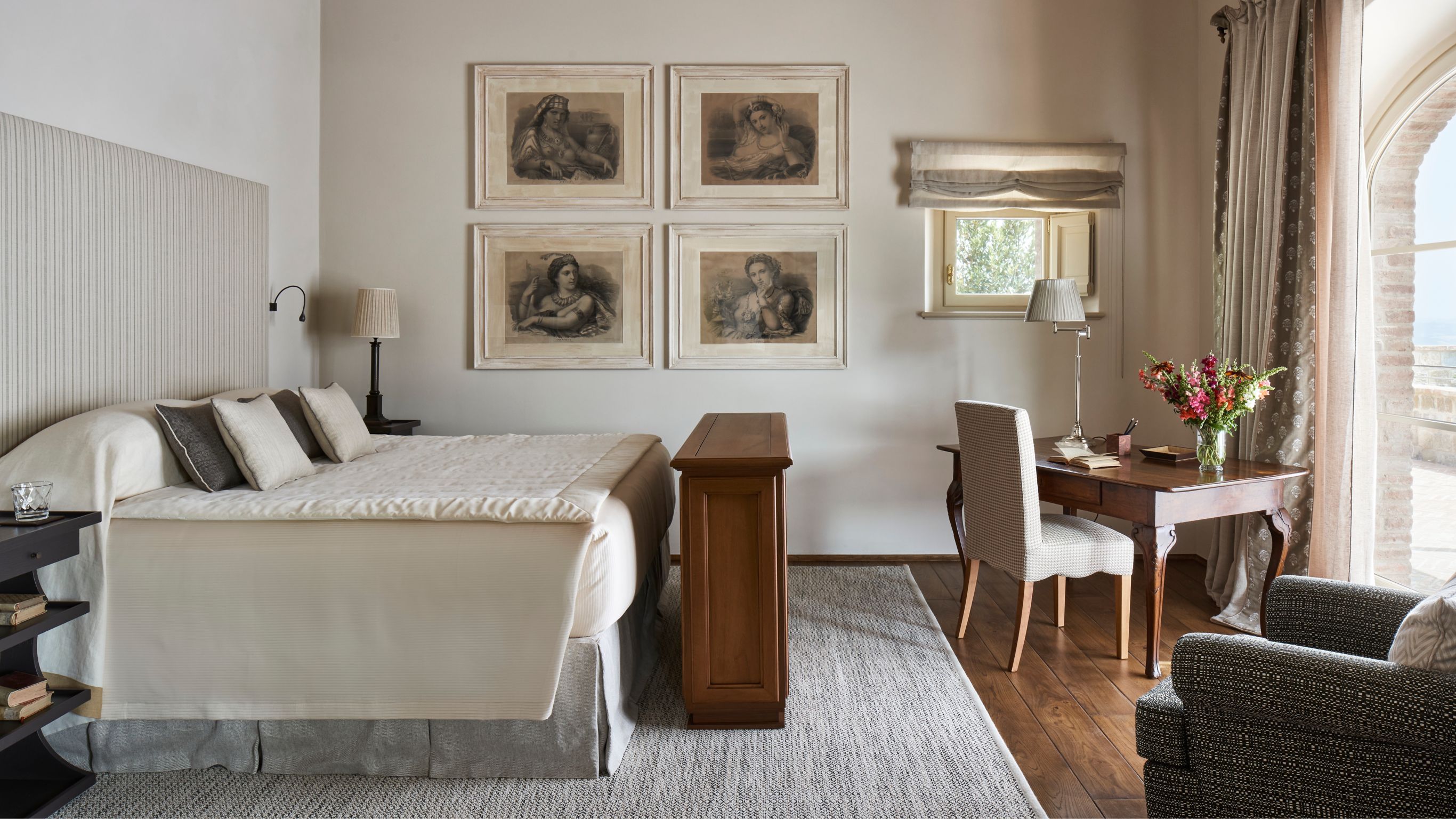 Villa bedroom with a neatly made bed, framed  artwork, a desk, and a chair
